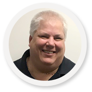 Smiling individual with short gray hair in a dark shirt, embodying SysAid’s ITSM excellence against a simple background. - SysAid