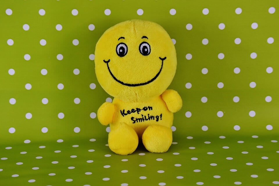 A cheerful yellow plush toy promotes SysAid's Help Desk solutions against a vibrant green polka dot backdrop. - SysAid