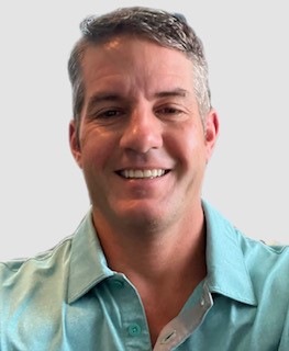 A smiling man in a teal shirt against a white background.