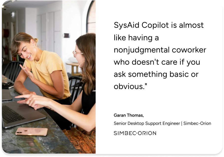 Two women discuss ITSM solutions at a desk, highlighting SysAid Copilot in a Simbec-Orion support engineer testimonial. - SysAid