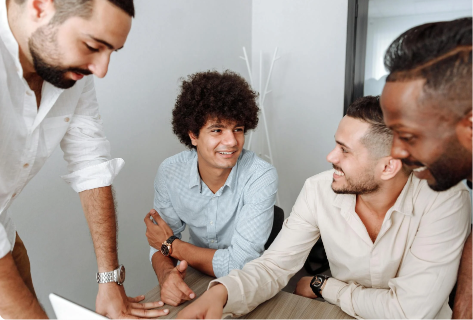 Four professionals discuss ITSM solutions around a table, collaborating in a modern office for improved service management. - SysAid