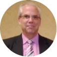 Professional man in suit, representing SysAid ITSM excellence and leadership, standing before a beige background. - SysAid